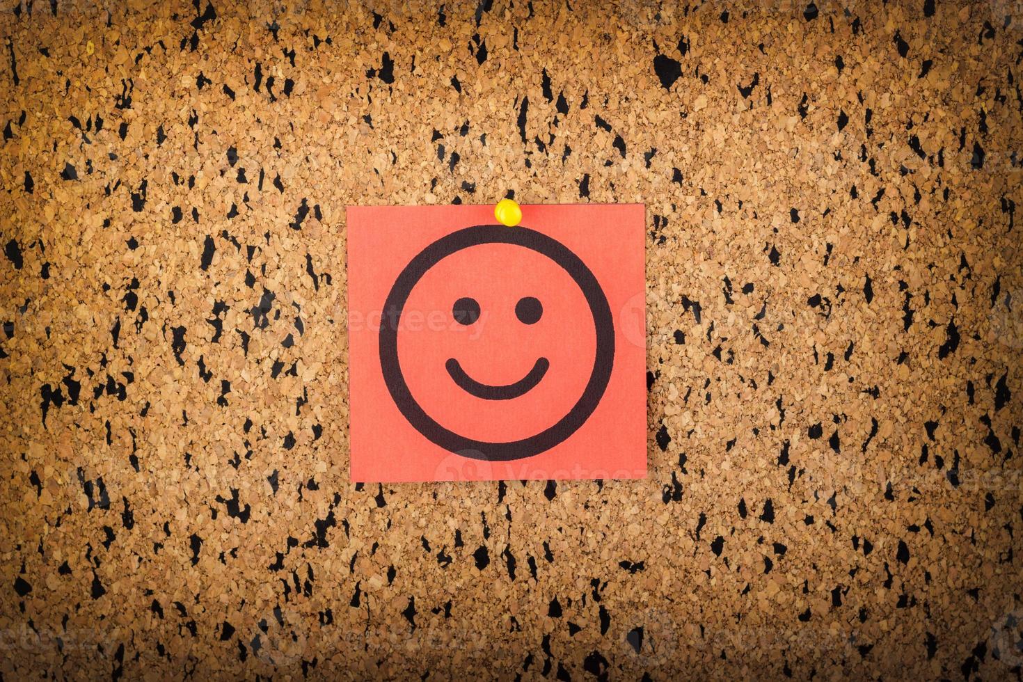 red paper with smiling face on corkboard. bulletin board. photo