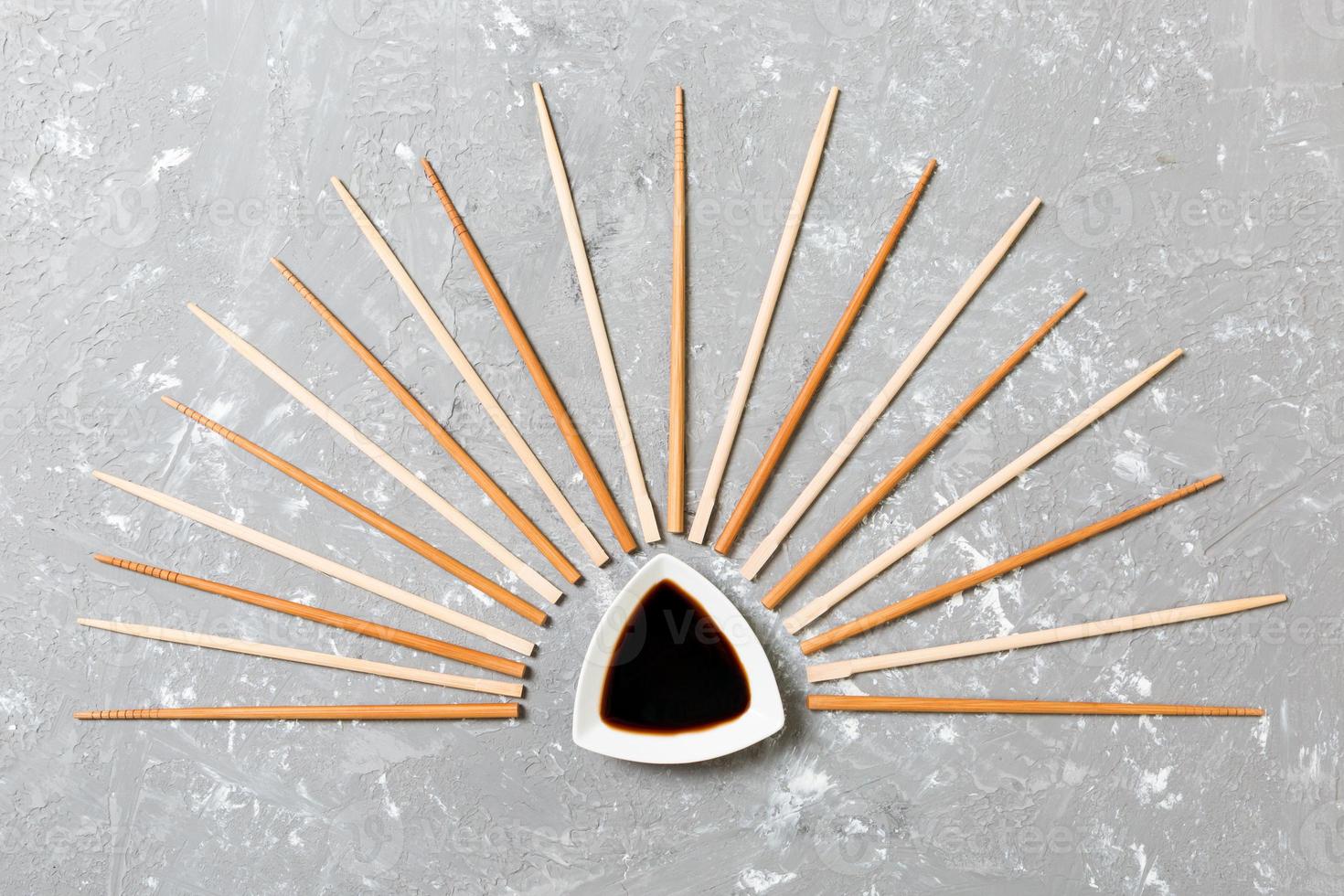 Many bamboo chopsticks with soy sauce on black cement stone background, top view with copy space. a lot of sushi sticks in the form of an ornament photo