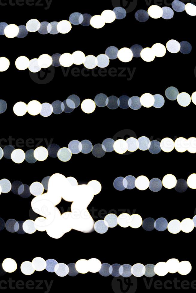 Abstract bokeh of white city lights on black background. defocused and blurred with star of light photo