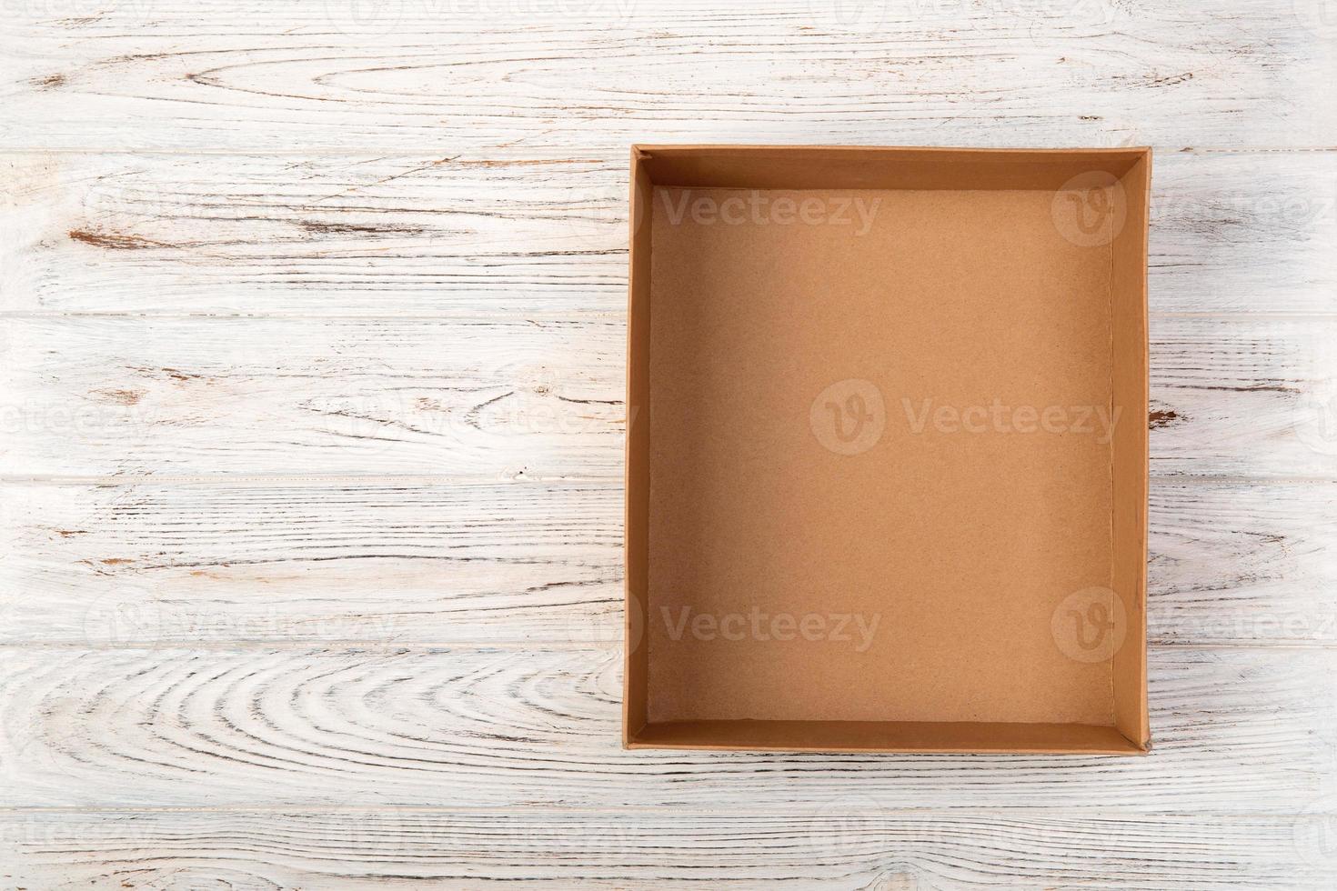 Opened brown blank cardboard box on wooden background, top view photo