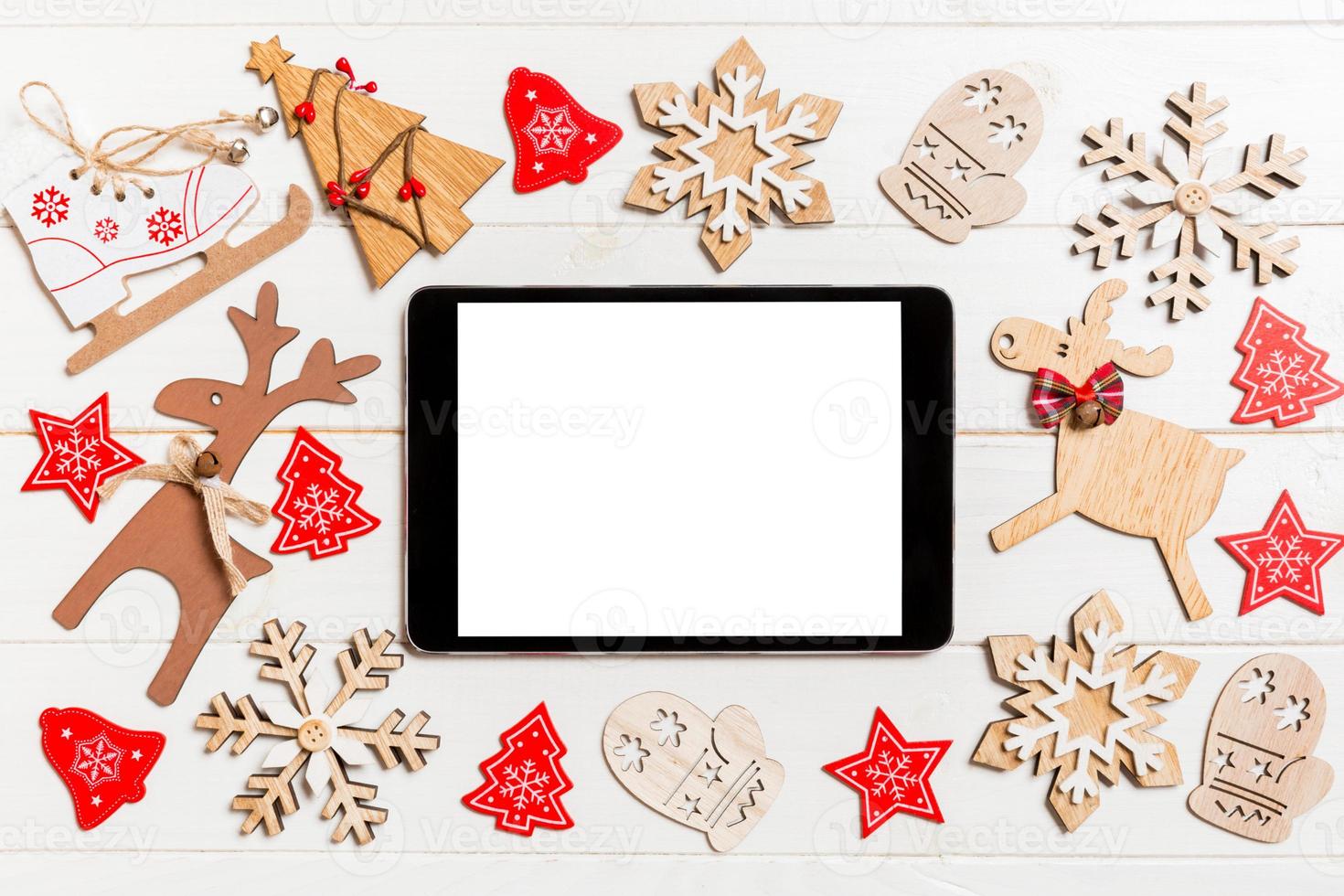 vista superior de la tableta sobre fondo de madera de vacaciones. decoraciones y juguetes de año nuevo. concepto de navidad foto