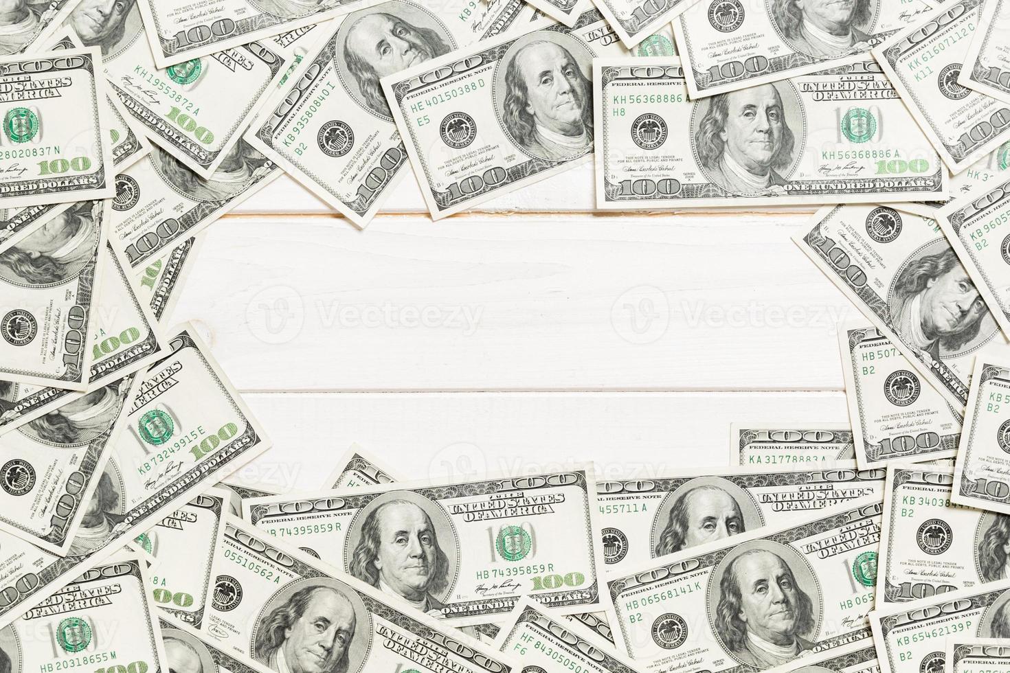 Frame of one hundred dollar bills with empty space for your design. Top view of business concept on white wooden background with copy space photo