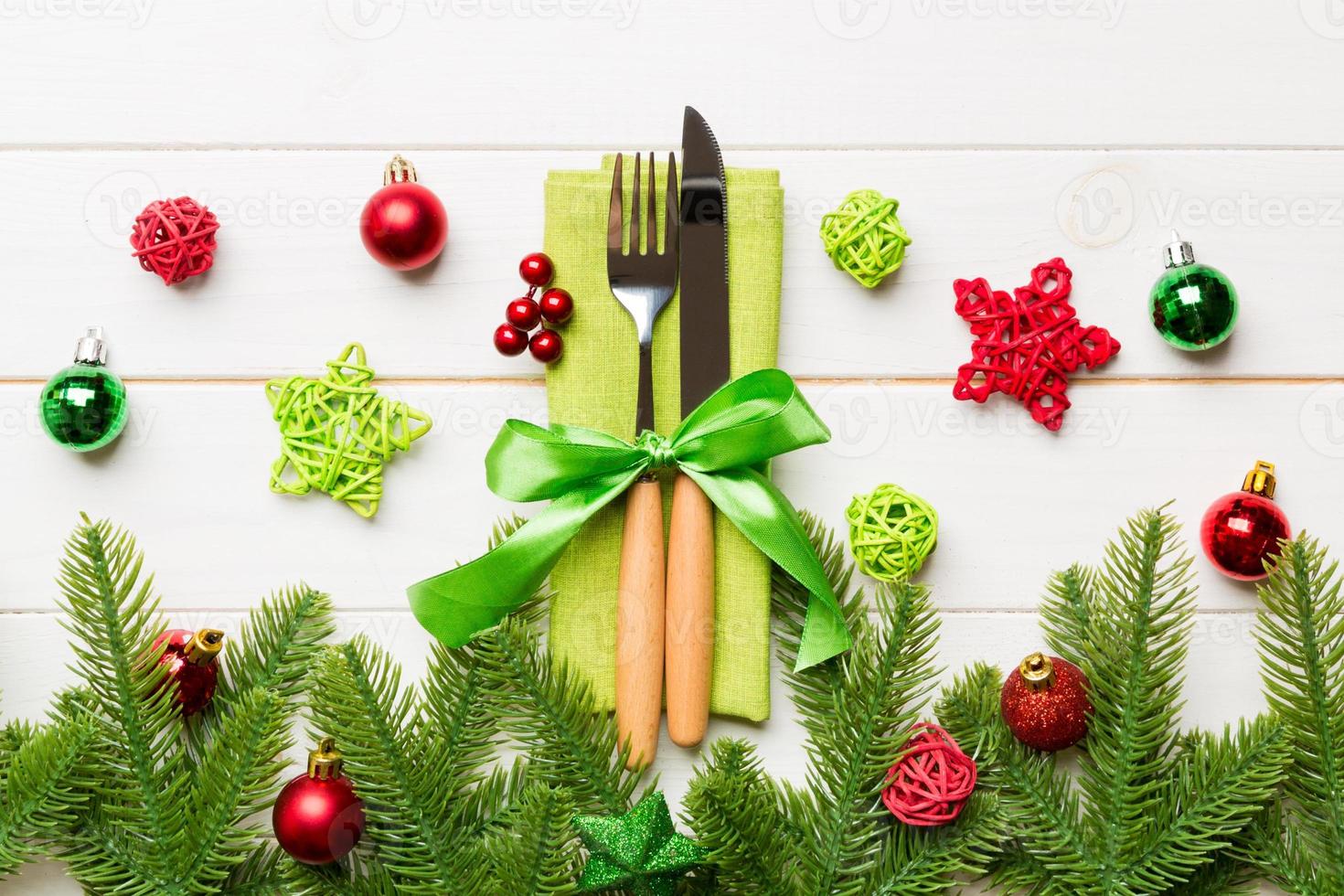 Top view of christmas decorations on wooden background. Fork and knife on napkin tied up with ribbon and empty space for your design. New year pattern concept photo