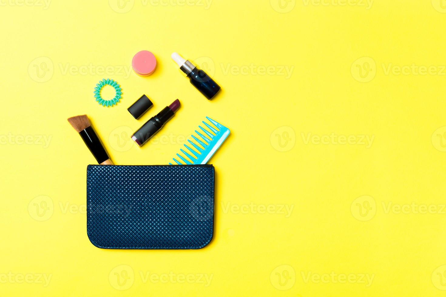 Make up products spilling out of cosmetics bag, on yellow background with empty space for your design photo
