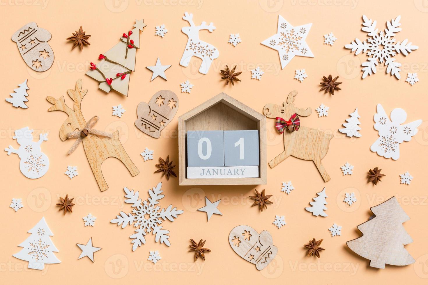 Festive decorations and toys on orange background. Top view of wooden calendar. The first of January. Happy New Year concept photo