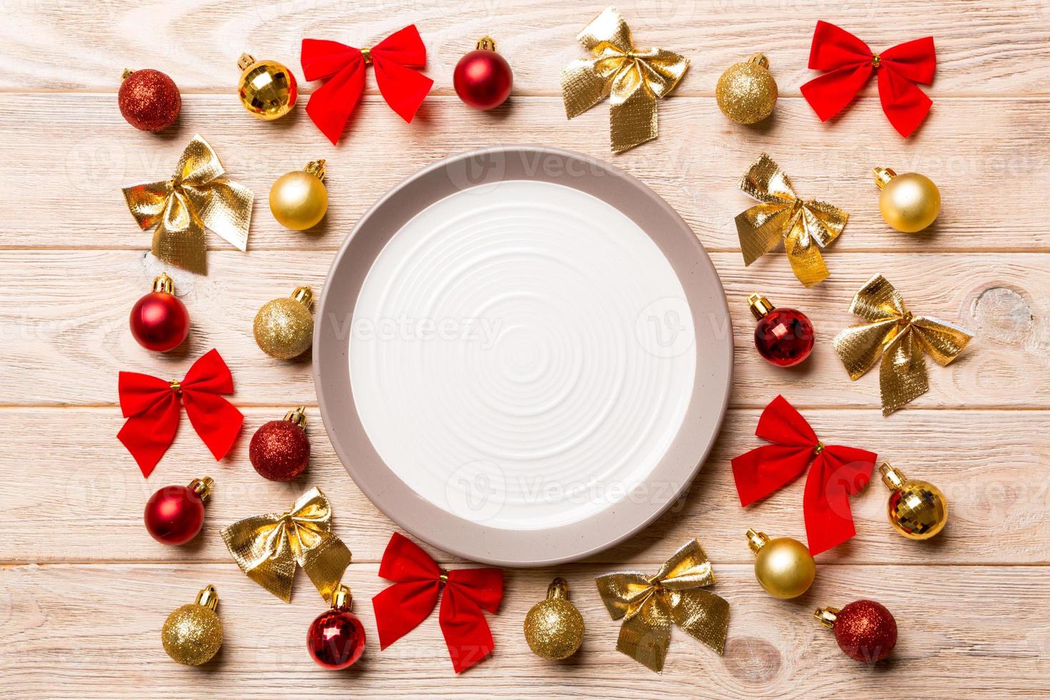 Top view of holiday dinner on wooden background. Plate, baubles and bows. Christmas Eve concept photo