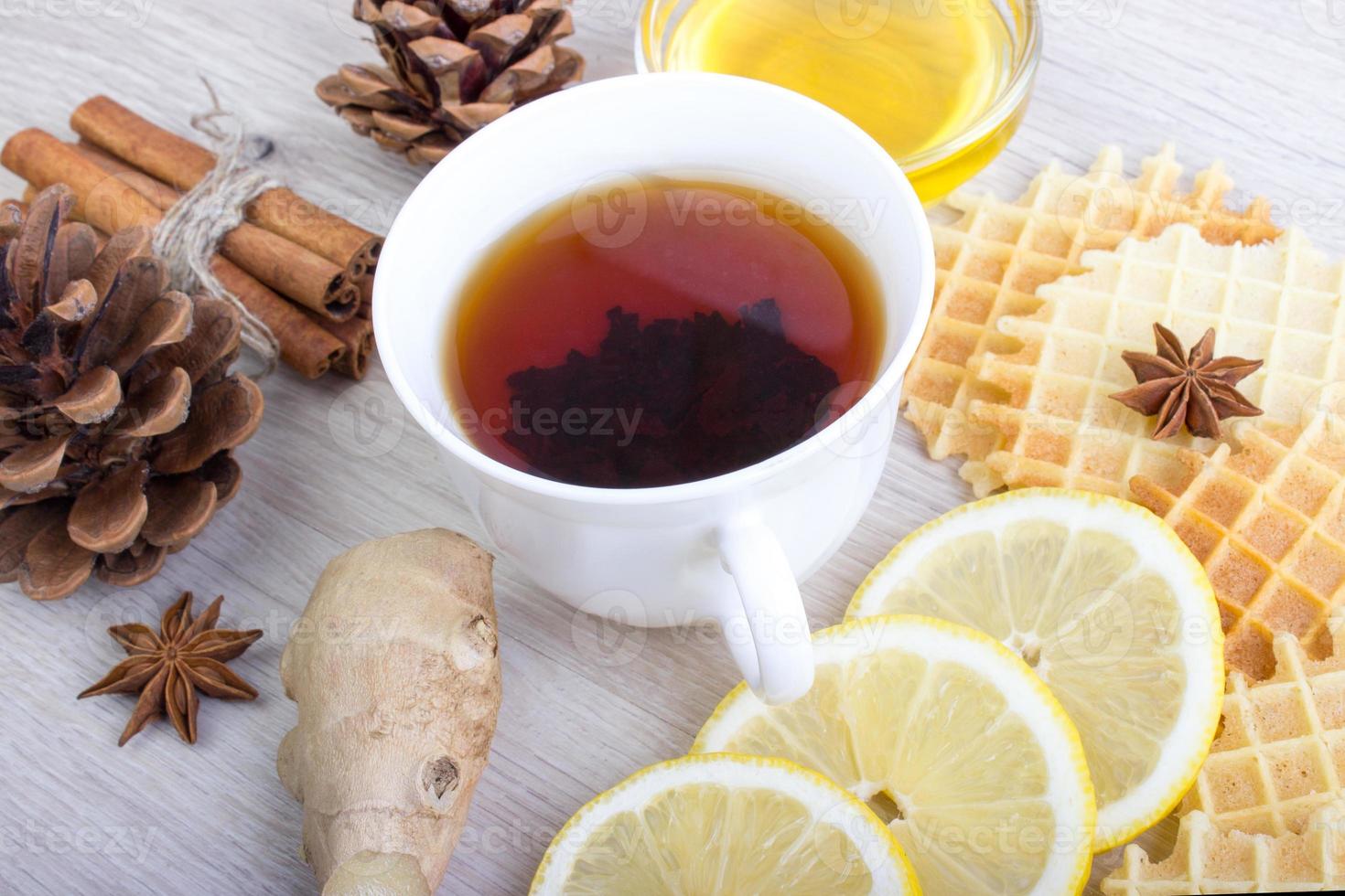 Cup of tea with honey, pinecone, badian, ginger, waffles and cinnamon photo