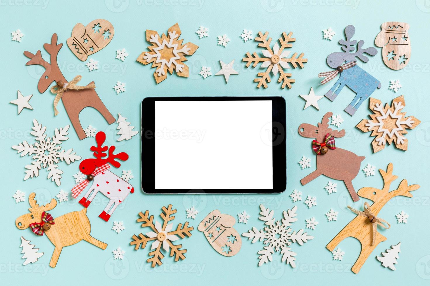 Top view of digital tablet on blue background made of holiday decorations and toys. Christmas ornament concept photo