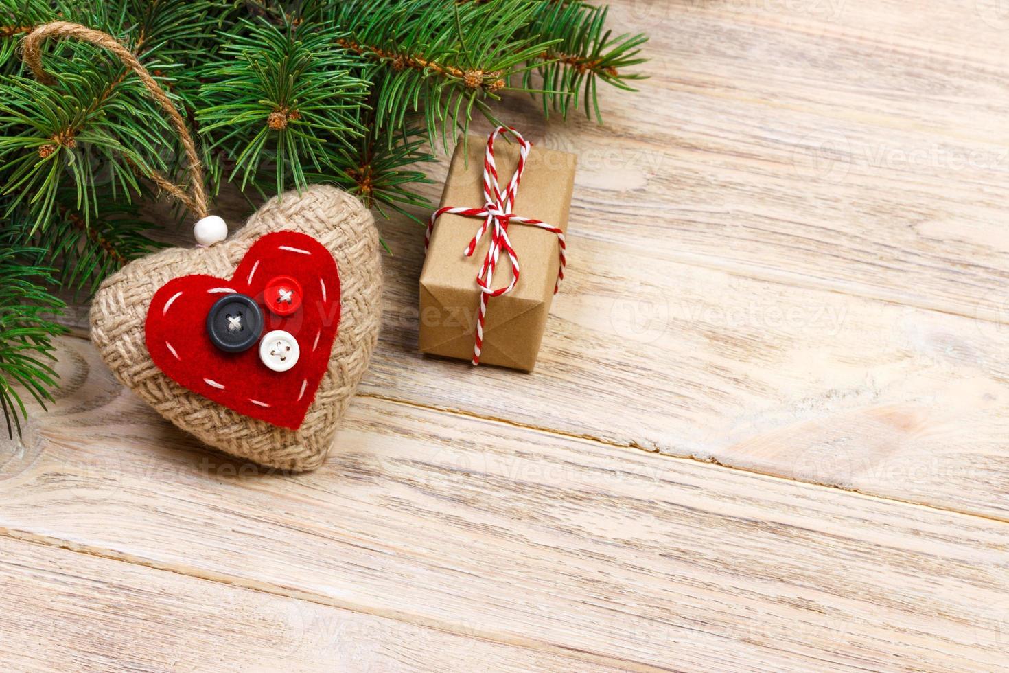 Christmas tree branch with red gift box and red hearts on wooden table. Top view with copy space photo