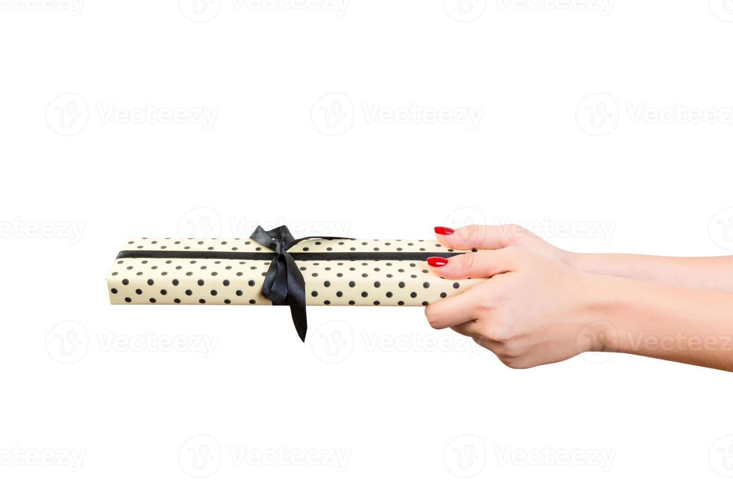 Woman hands give wrapped Christmas or other holiday handmade present in yellow paper with black ribbon. Isolated on white background, top view. thanksgiving Gift box concept photo