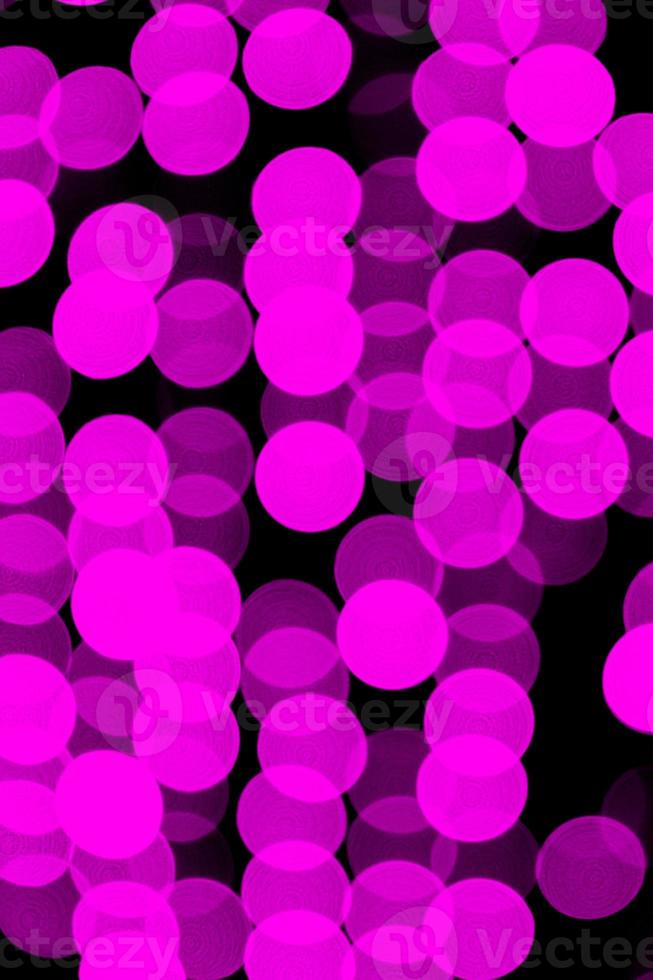 Unfocused abstract violet bokeh on black background. defocused and blurred many round light photo