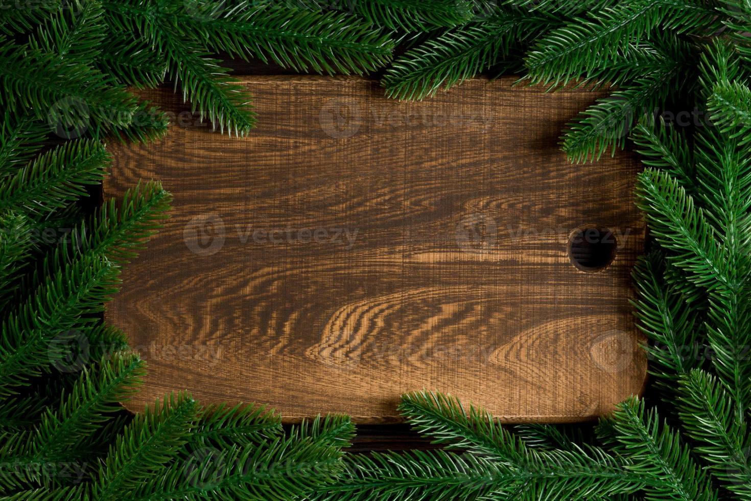 Top view of wooden plate decorated with fir tree branches. New Year dinner concept with empty space for your design photo