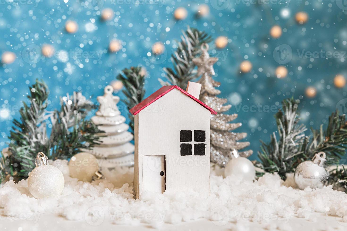 Abstract Advent Christmas Background. Toy model house and winter decorations ornaments on blue background with snow. Christmas with family at home concept. photo