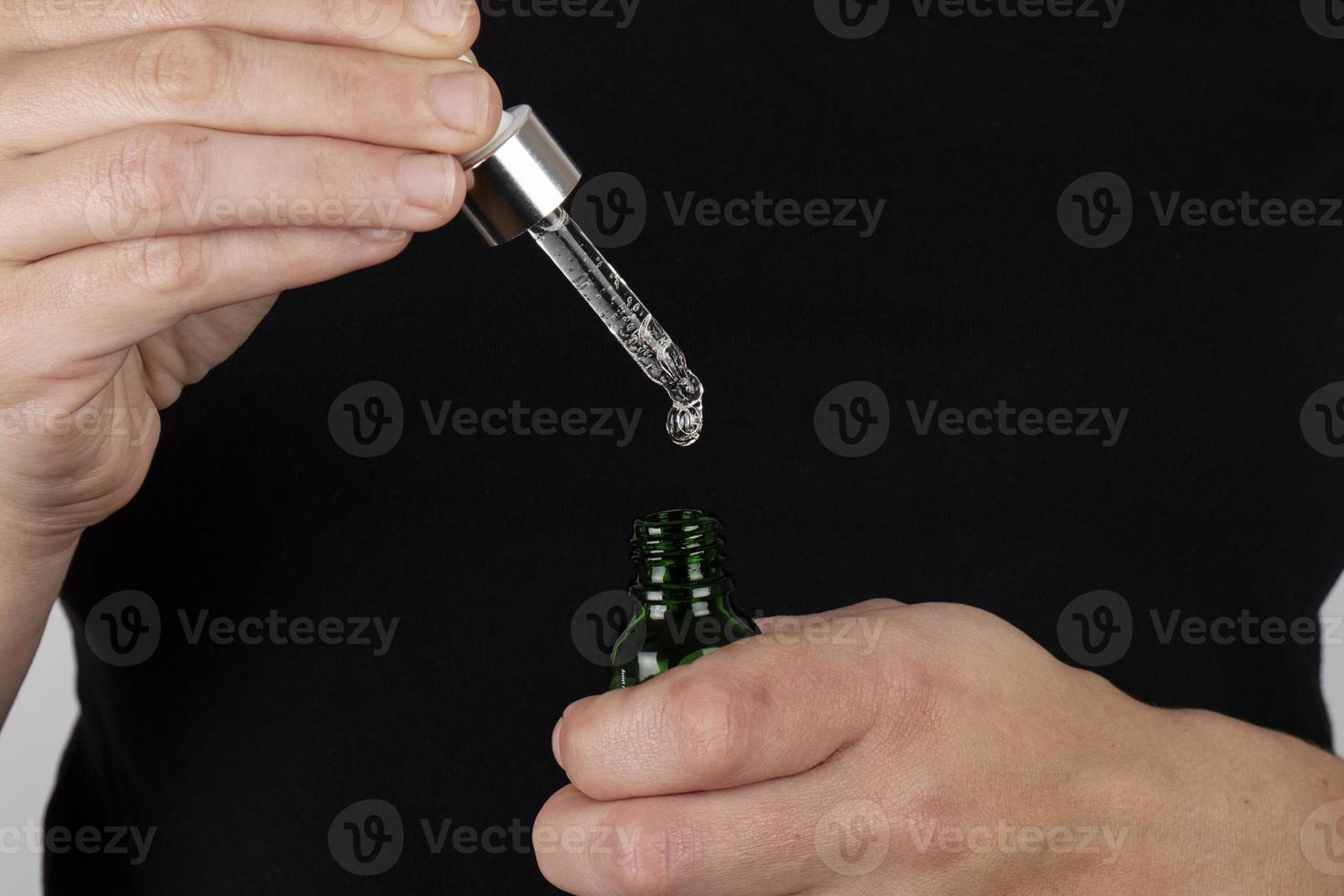 hand holds a pipette and a bottle of medicine in his hands photo