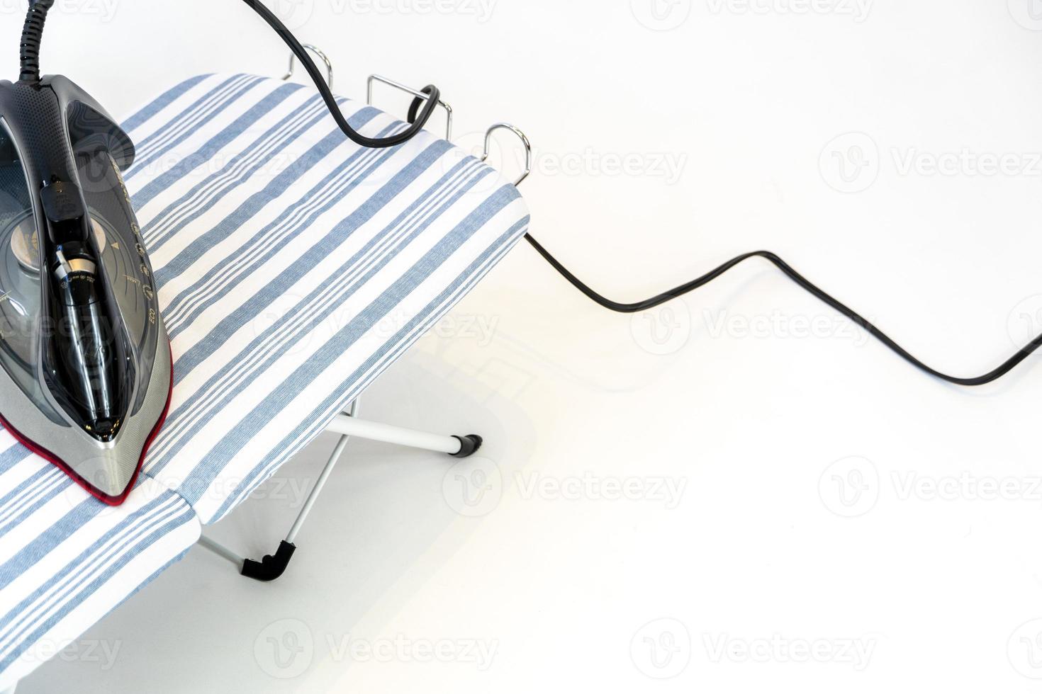 new clothes iron on white background, red ceramic iron, and blue fabric ironing board base photo