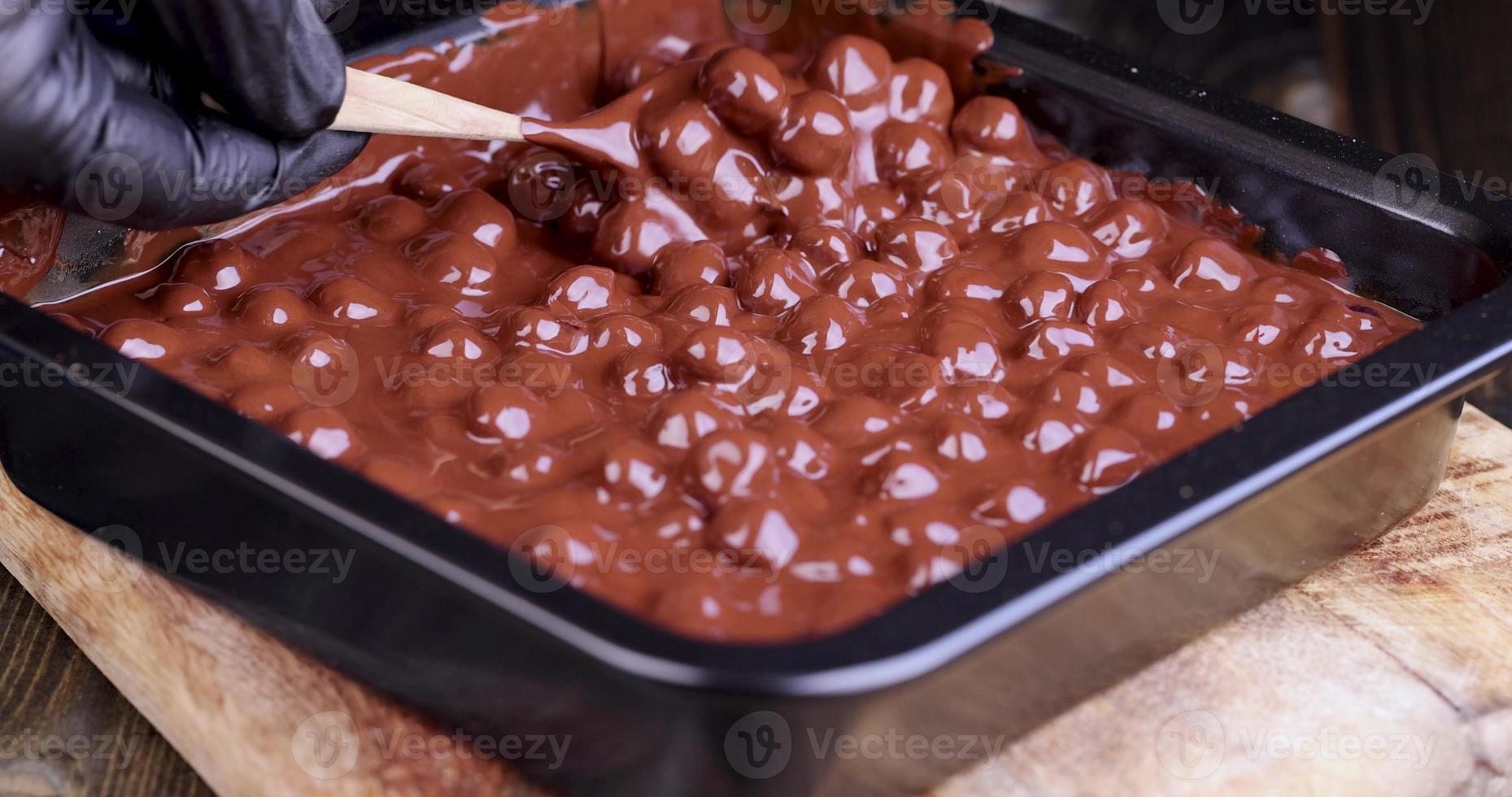 adding roasted hazelnuts to melted liquid chocolate photo