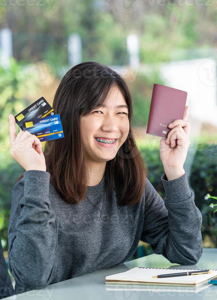 Young woman sitting showing passport and credit card photo