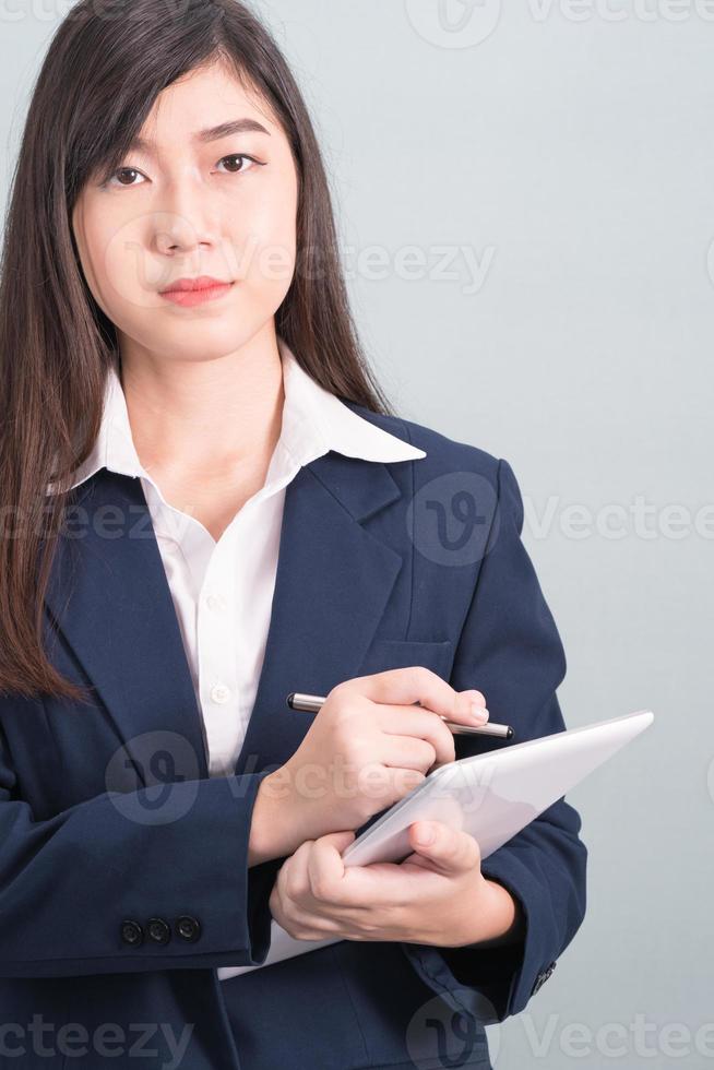 Woman in suit using computer digital tablet on gray photo
