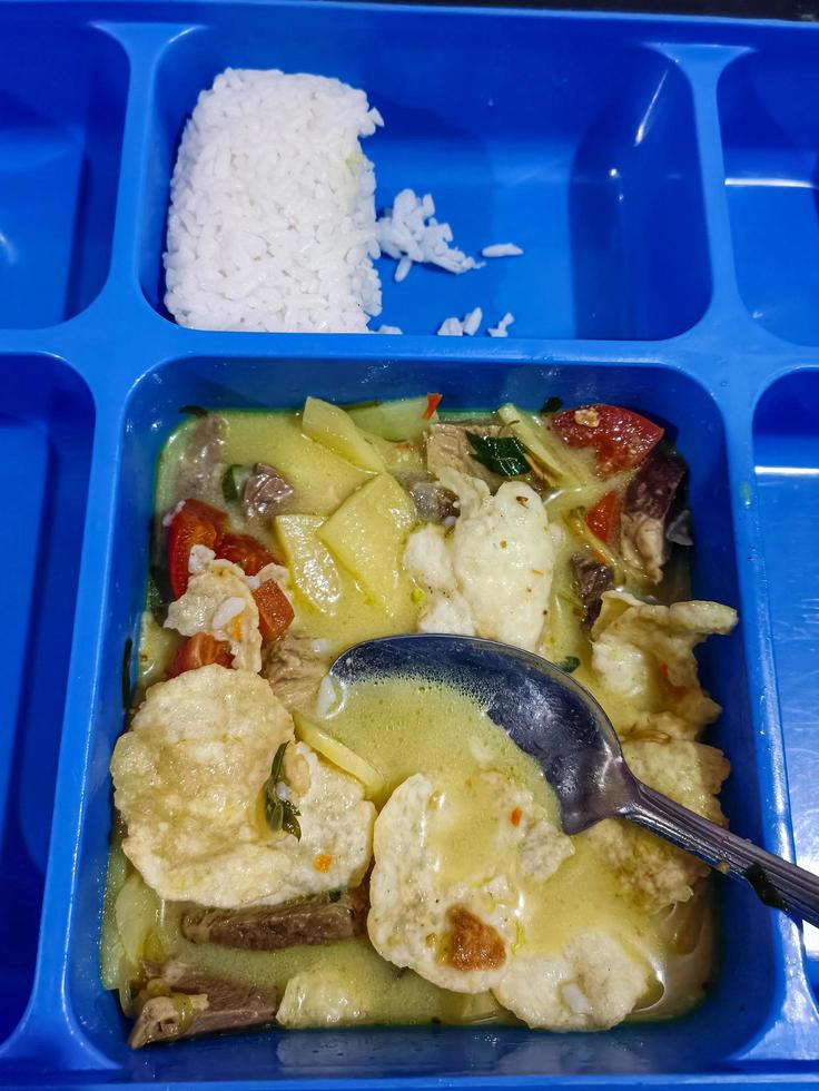 Indonesian food has Soto Betawi which is served with rice, which is served in a blue dining area photo
