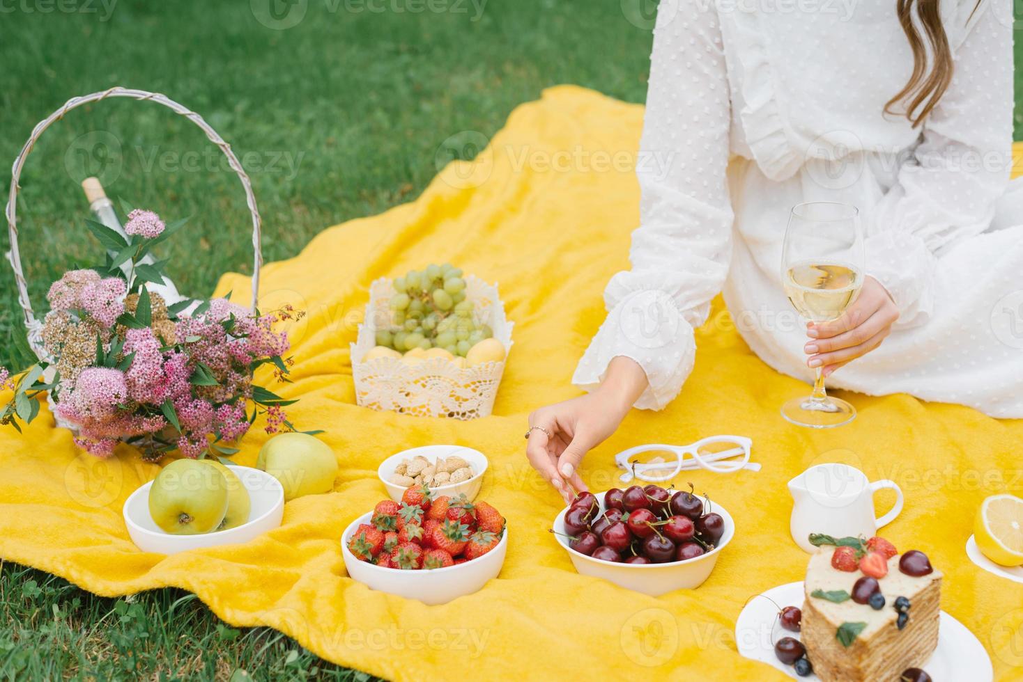 picnic de verano en la naturaleza con pastel, jugo y fruta en una manta amarilla entre la hierba verde. actividades al aire libre foto