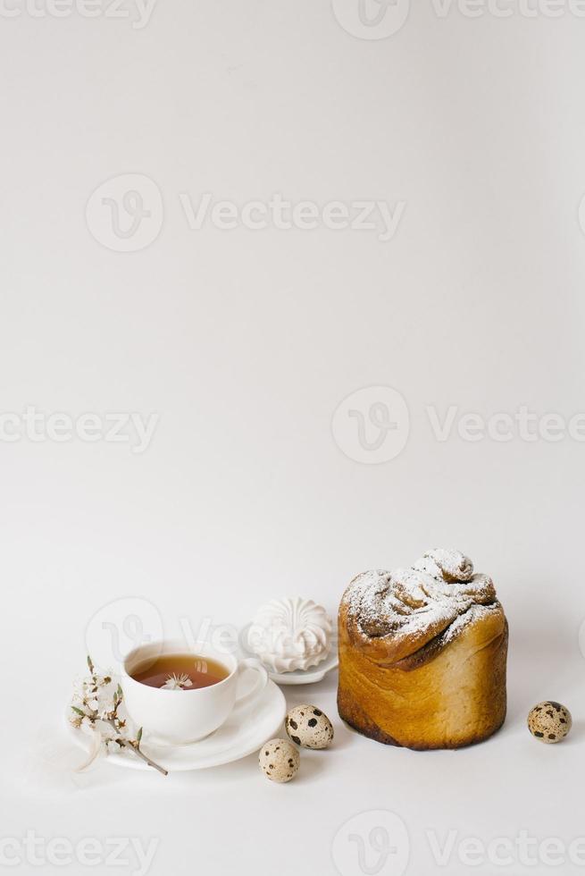 Easter sweet bread, cake and eggs with white apple flowers, a cup of tea. Festive breakfast concept with copy space. photo