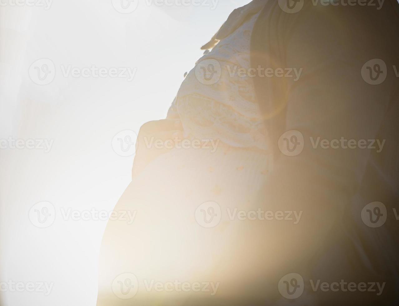 Young beautiful pregnant woman standing near window at home photo