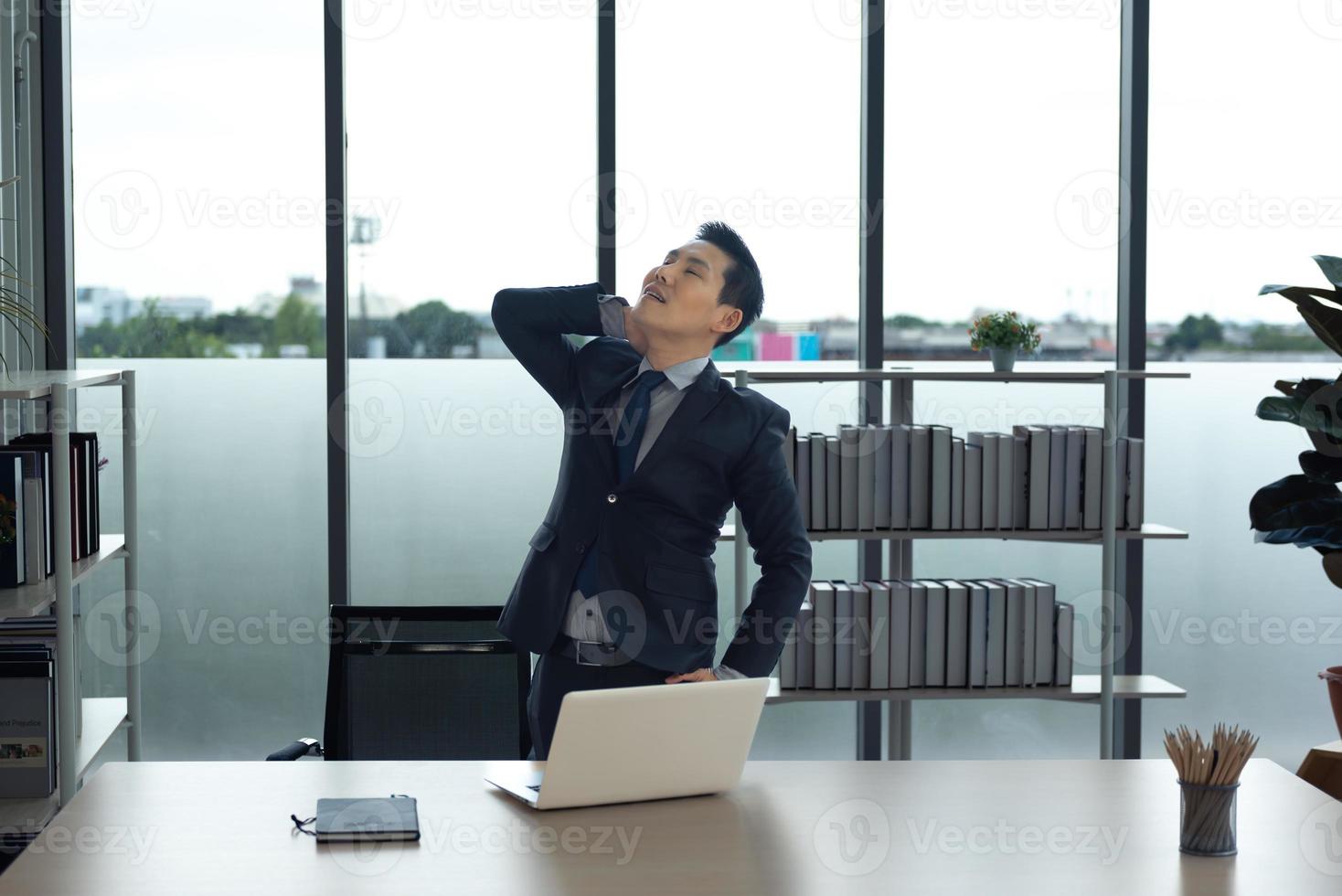 Asian Businessman in the office relaxing, stretching arm and neck muscle , waiting for working and meeting. photo