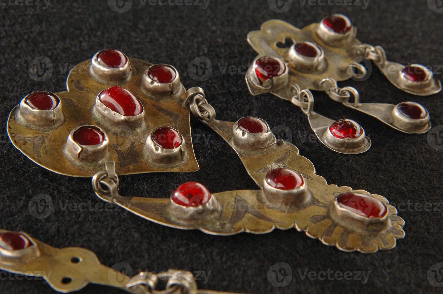 A Vintage brooch with precious, red stones isolated on a black background, Central Asian photo