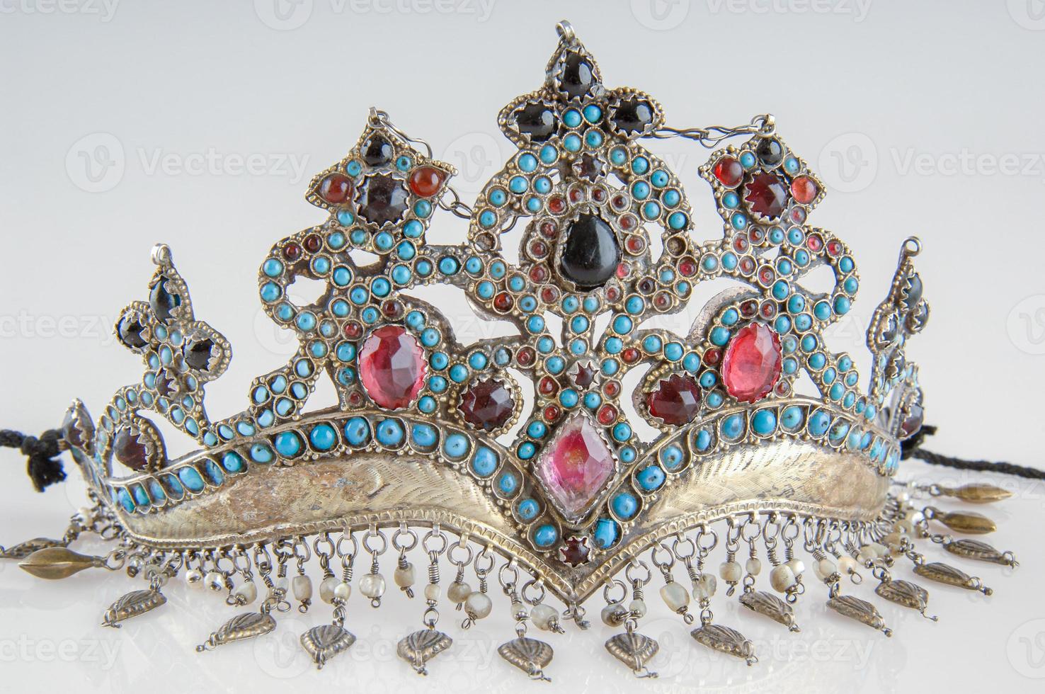 A fancy, antique tiara with precious, colorful stones isolated on a white background, close-up photo