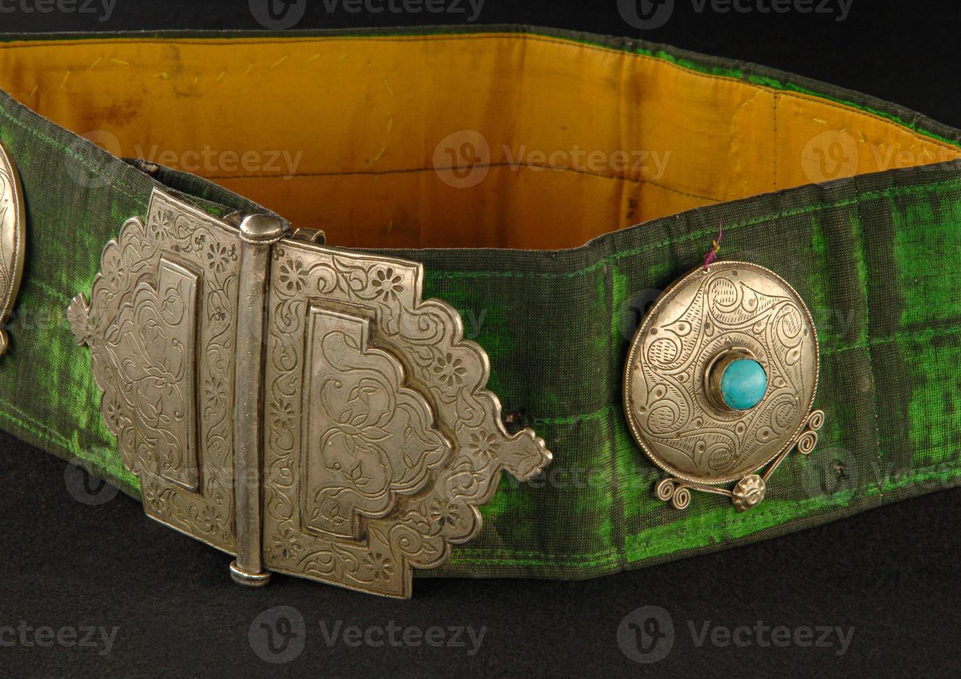 A Green, antique belt with precious stones isolated on a black background photo