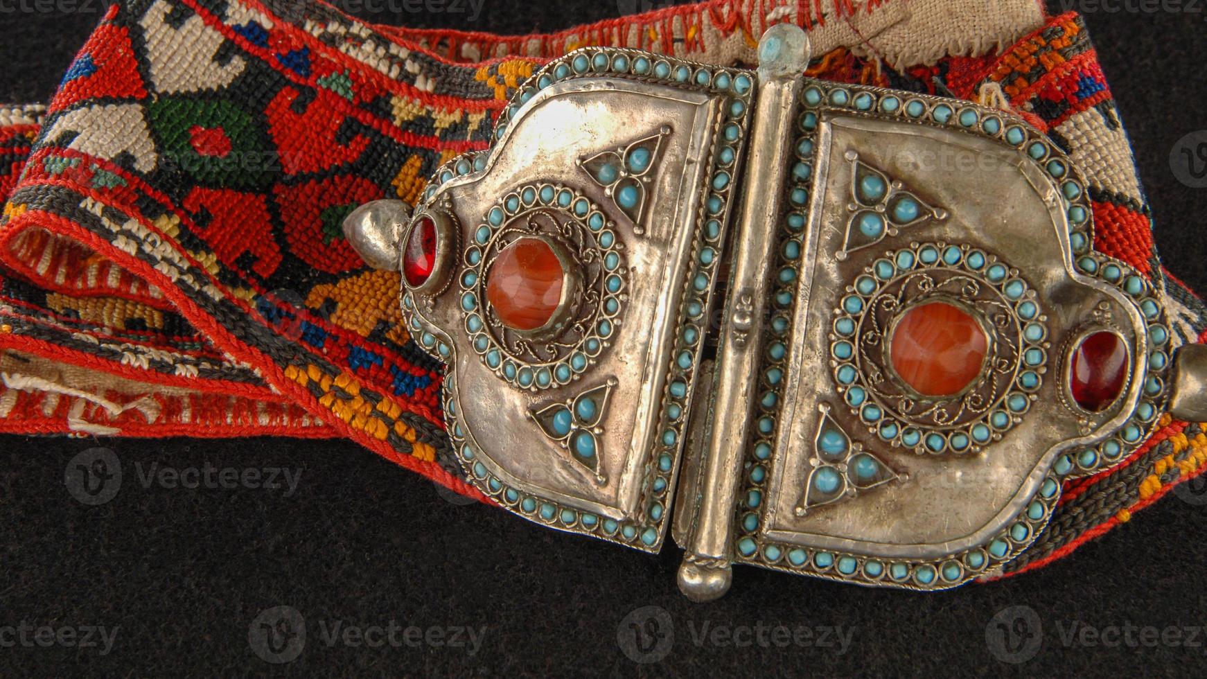 An antique belt in traditional red, patterns with precious stones isolated on a black background photo