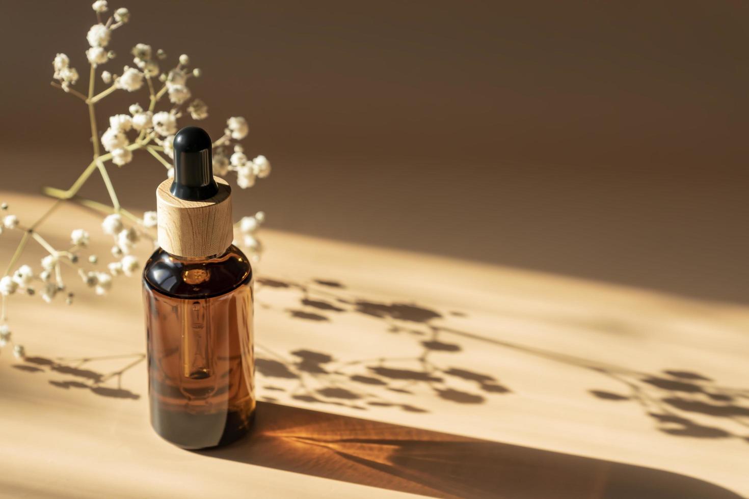 Amber bottle with dropper pipette on beige background with daylight and beautiful shadows. Skincare serum or essential oil natural cosmetic. Beauty concept for face and body care. Mockup photo