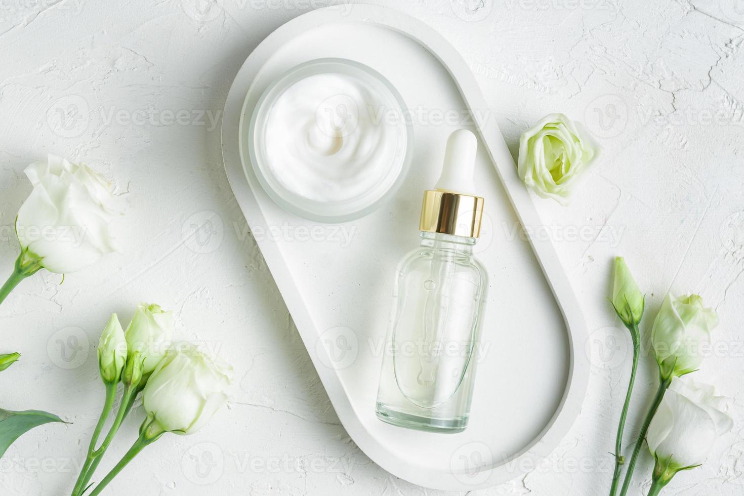 cosmetic bottle containers with blooming eustoma flowers on concrete tray, blank packaging, branding mockups photo