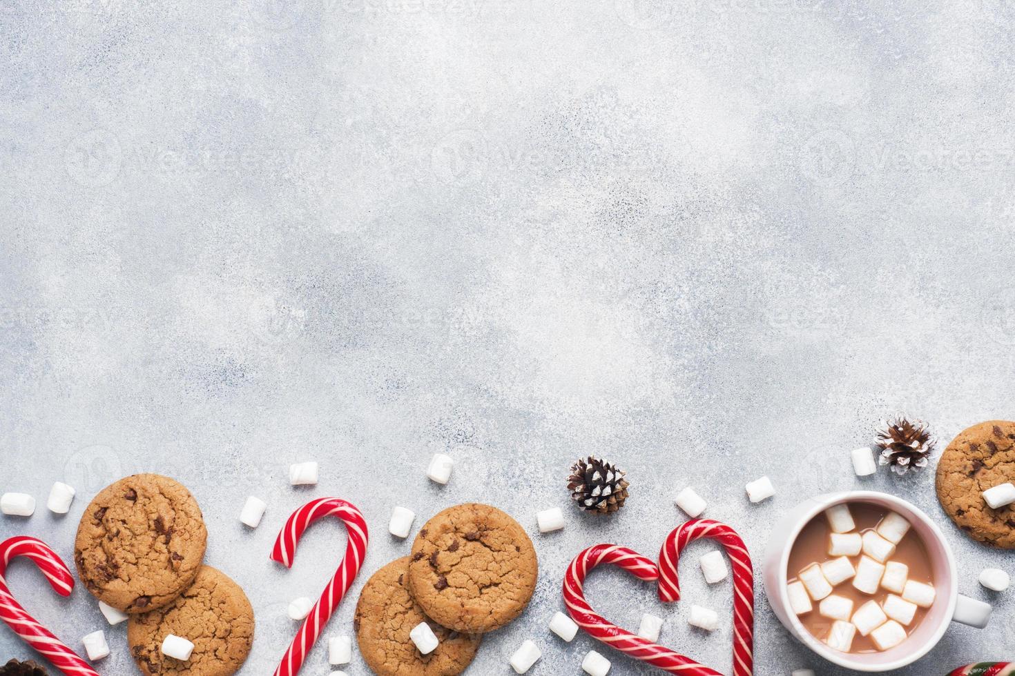 The chocolate chip cookie, Christmas cane caramel Cup cocoa and marshmallow cones Decorations on a gray background. Copy space Frame. photo