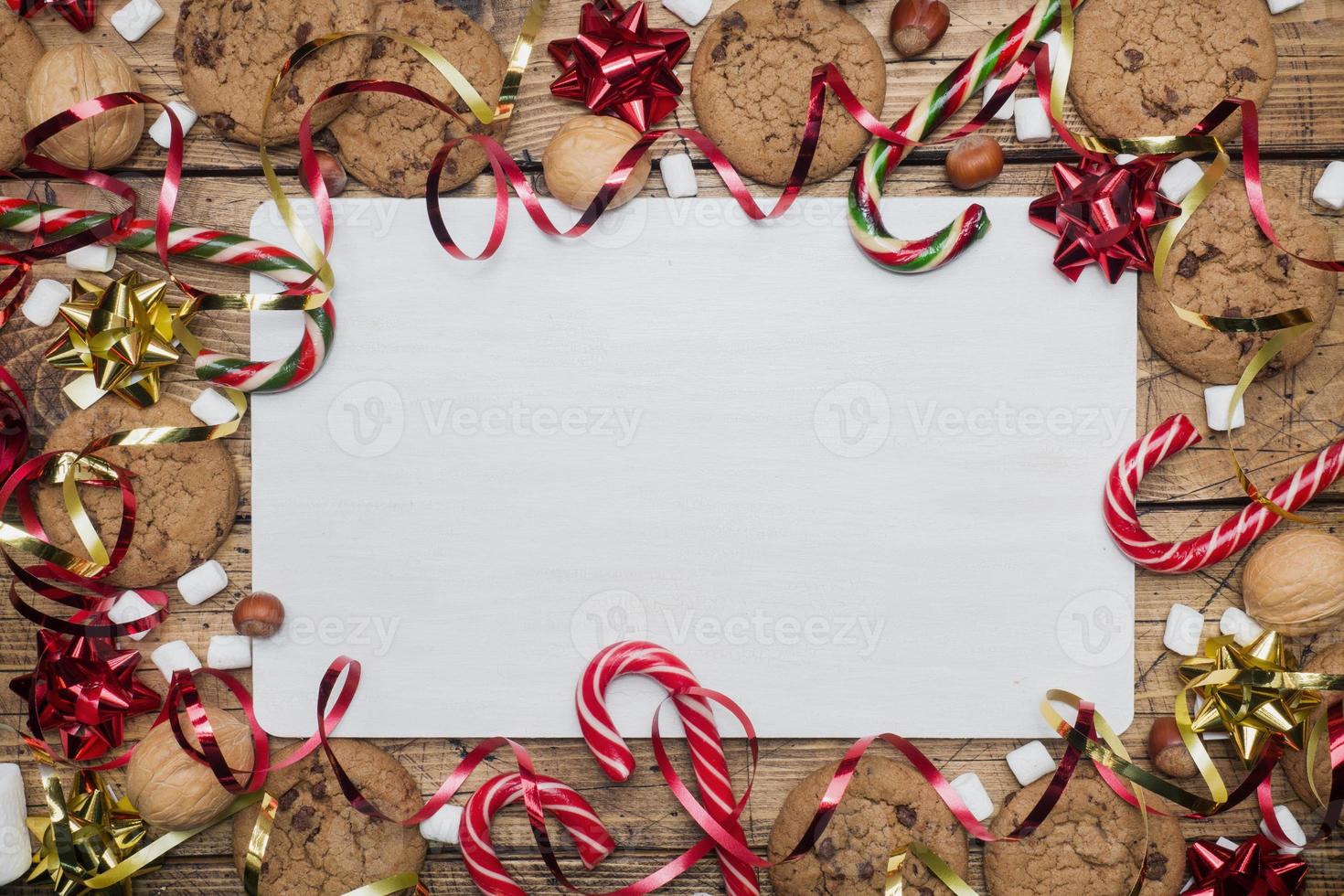 Chocolate chip cookies Christmas canes caramel red gold scenery and marshmallow on wooden background. Copy space Frame. photo