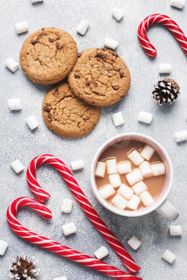 The chocolate chip cookie, Christmas cane caramel Cup cocoa and marshmallow cones Decorations on a gray background. Close up photo