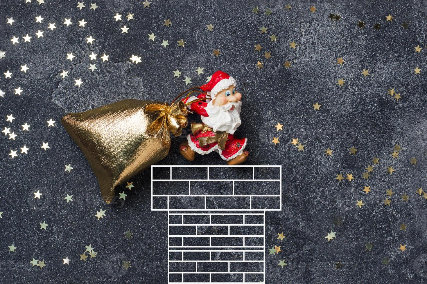 The concept of Christmas night. Santa drags a bag of gifts into the chimney. Dark starry background. photo