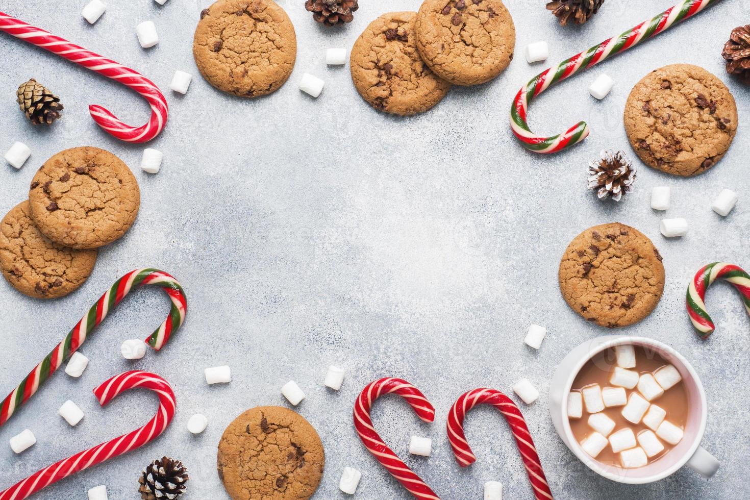 The chocolate chip cookie, Christmas cane caramel Cup cocoa and marshmallow cones Decorations on a gray background. Copy space Frame. photo