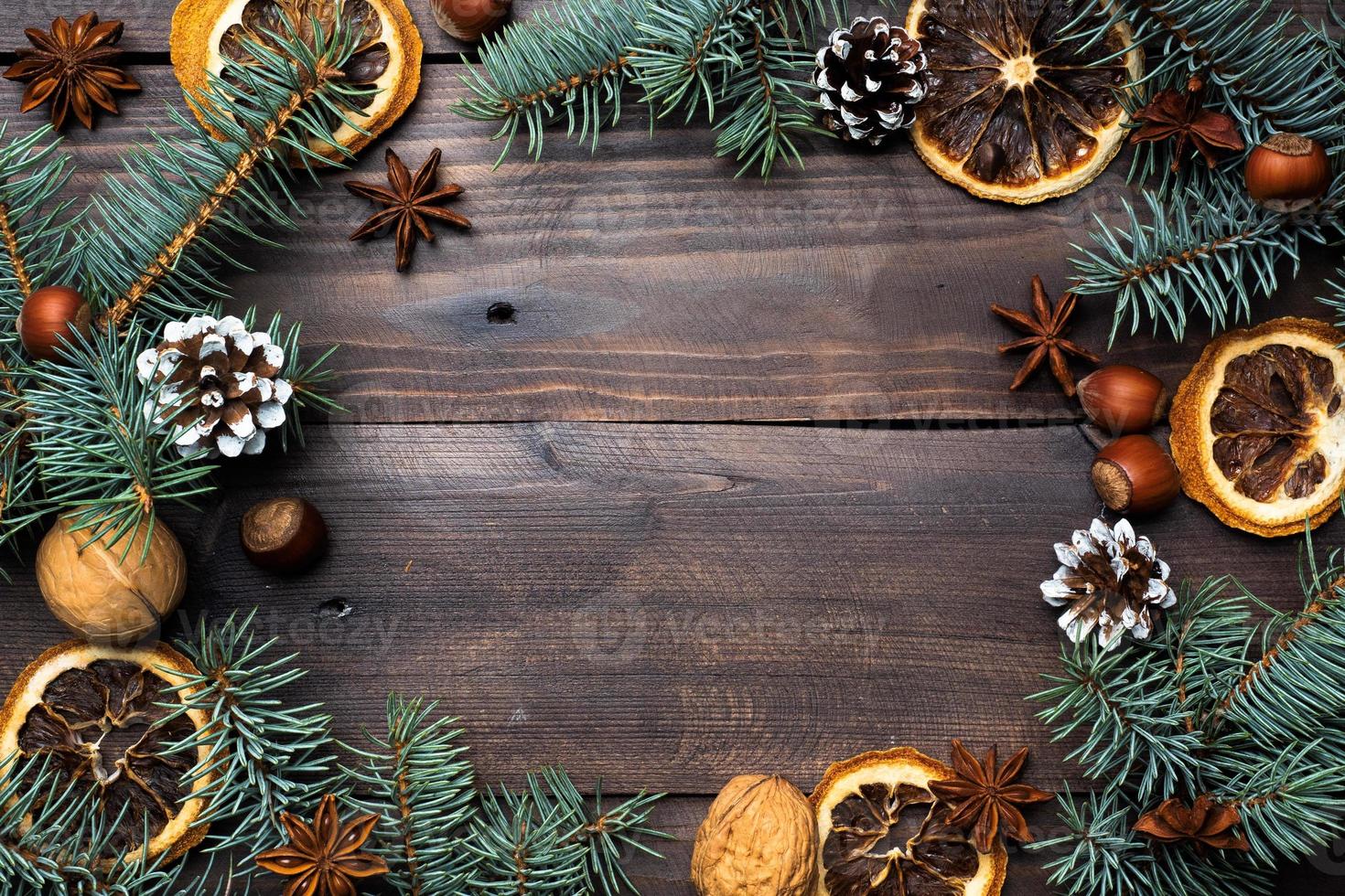 Frame of Christmas tree cones oranges nuts on dark wooden background. Copy space. Flat lay. photo