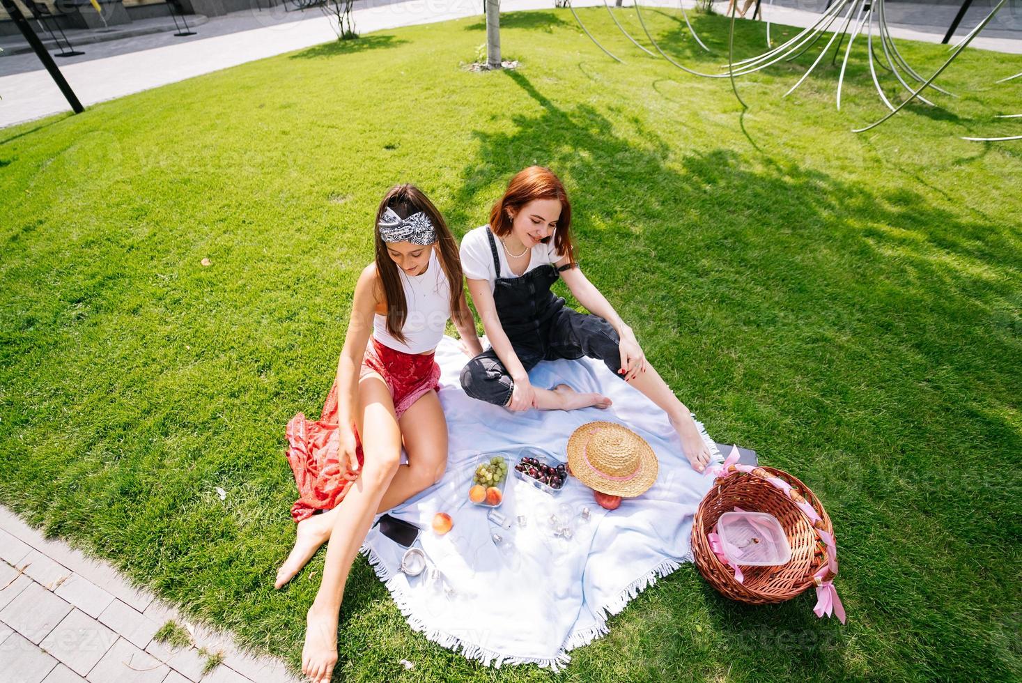 Two women having picnic together, sitting on the plaid photo