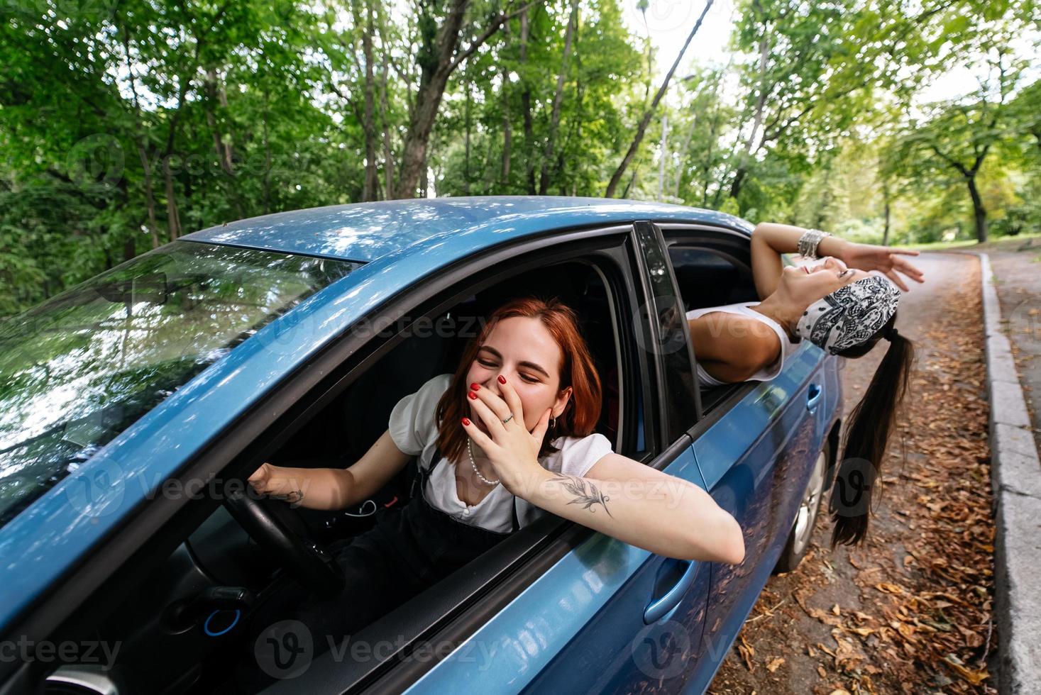 Two girlfriends fool around and laughing together in a car photo