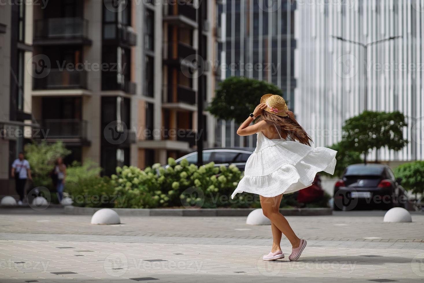 Beautiful pretty woman in white dress walking at city street photo