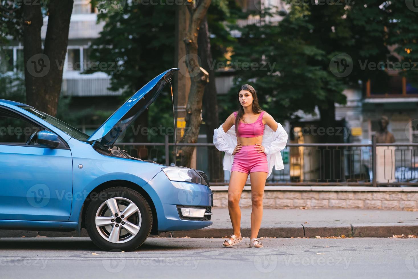 mujer con coche roto en la carretera. buscar ayuda foto