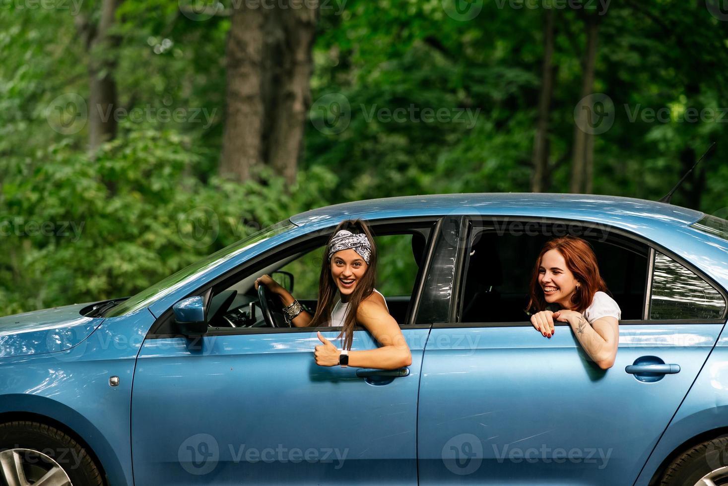 Two girlfriends fool around and laughing together in a car photo