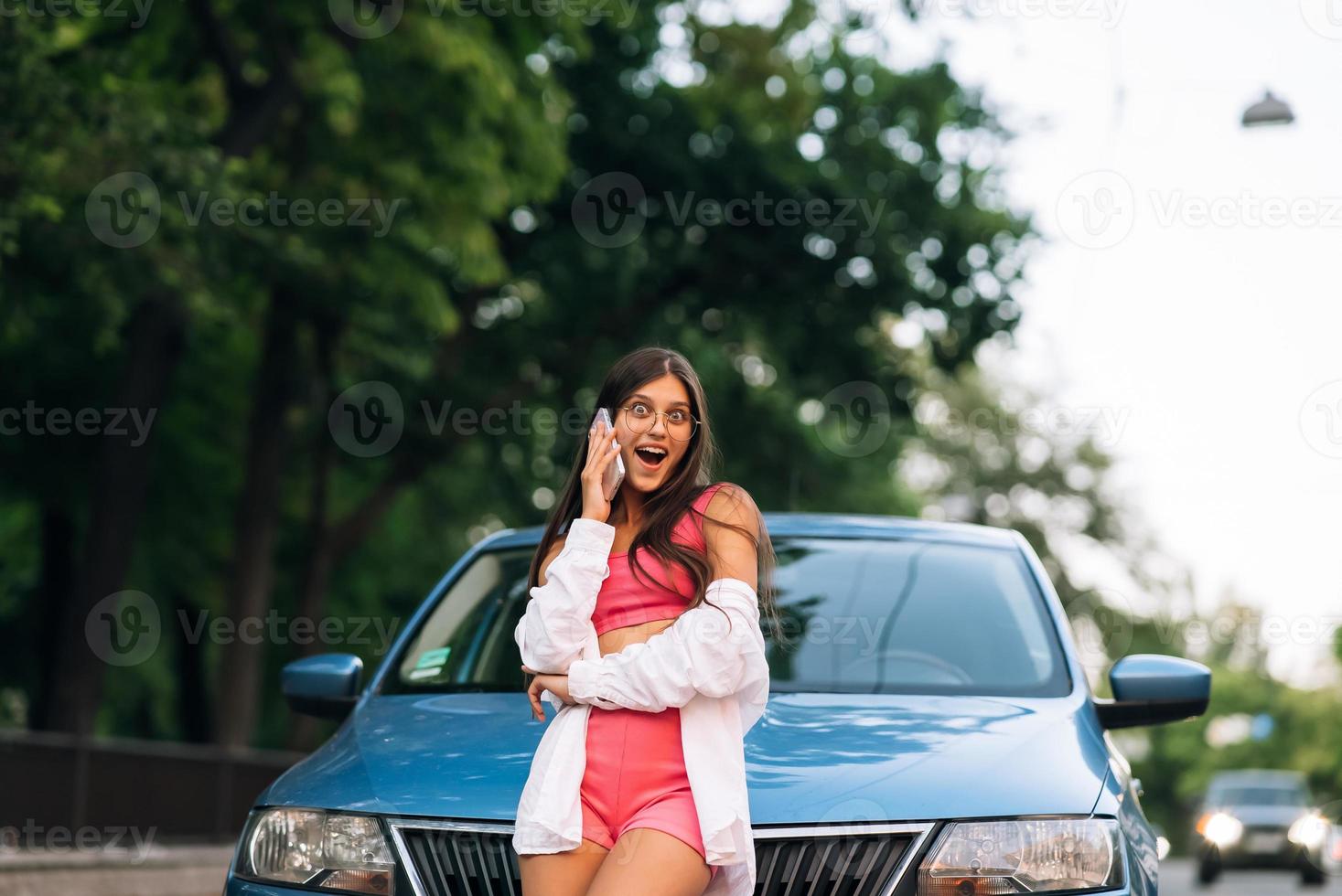 Woman talking on phone near car at the street photo