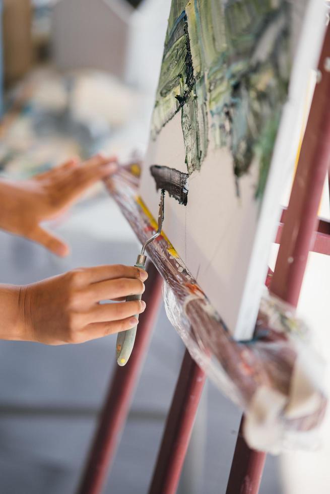 Close-up of a woman's hand applying paint to a canvas photo