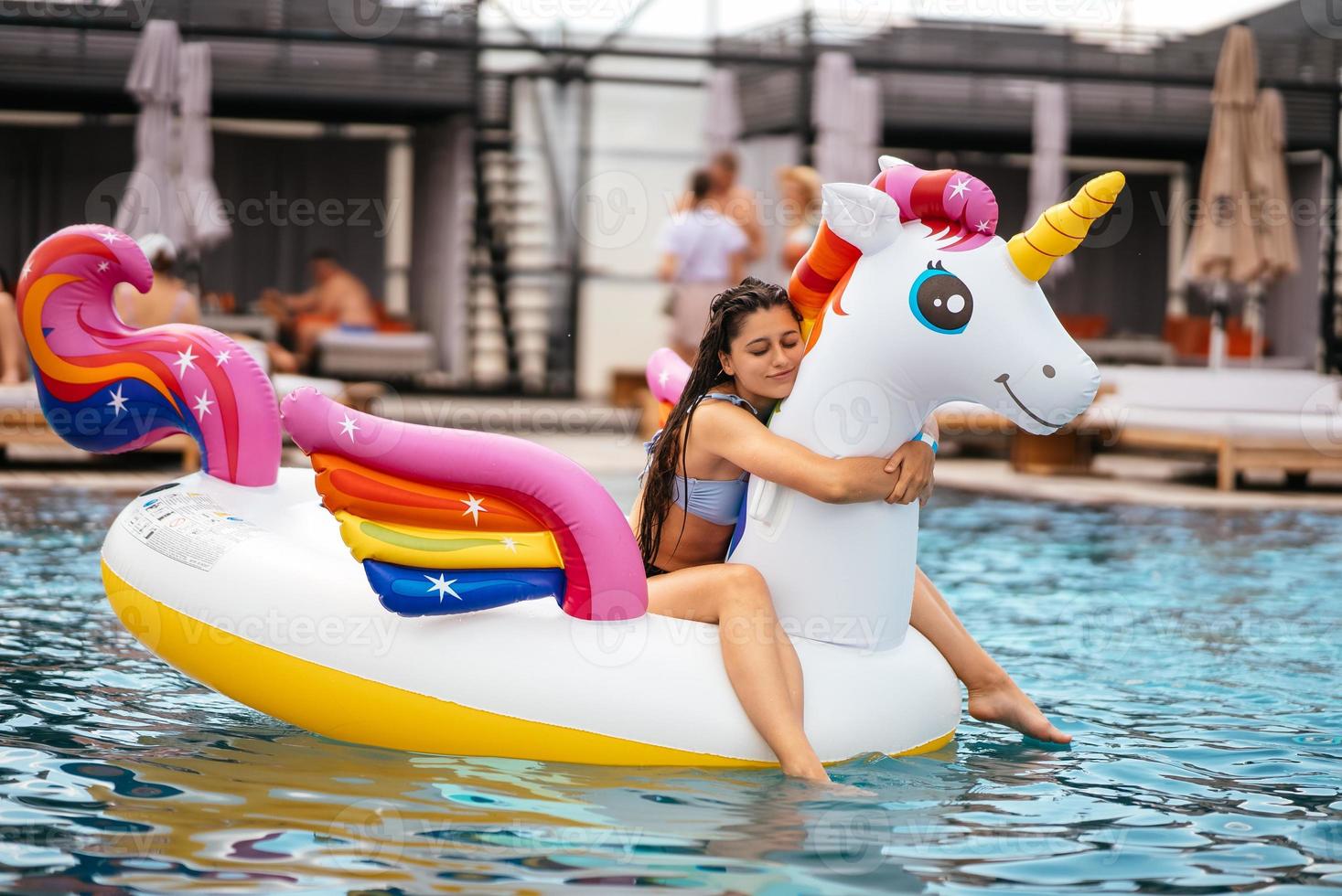 Woman on inflatable unicorn toy mattress float in pool. photo