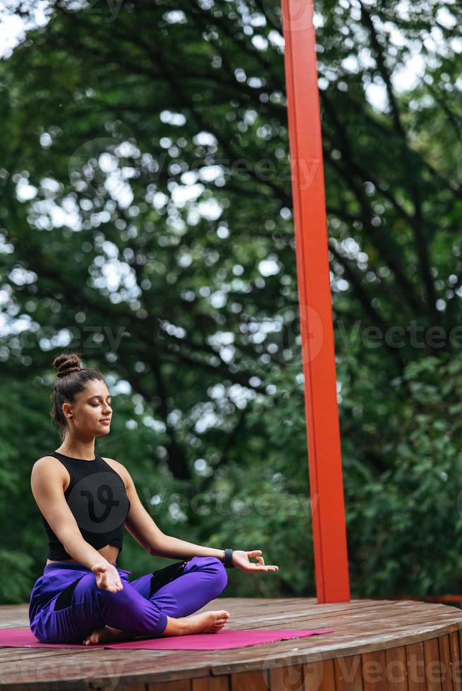 mujer joven está practicando yoga sentada en la posición de loto foto