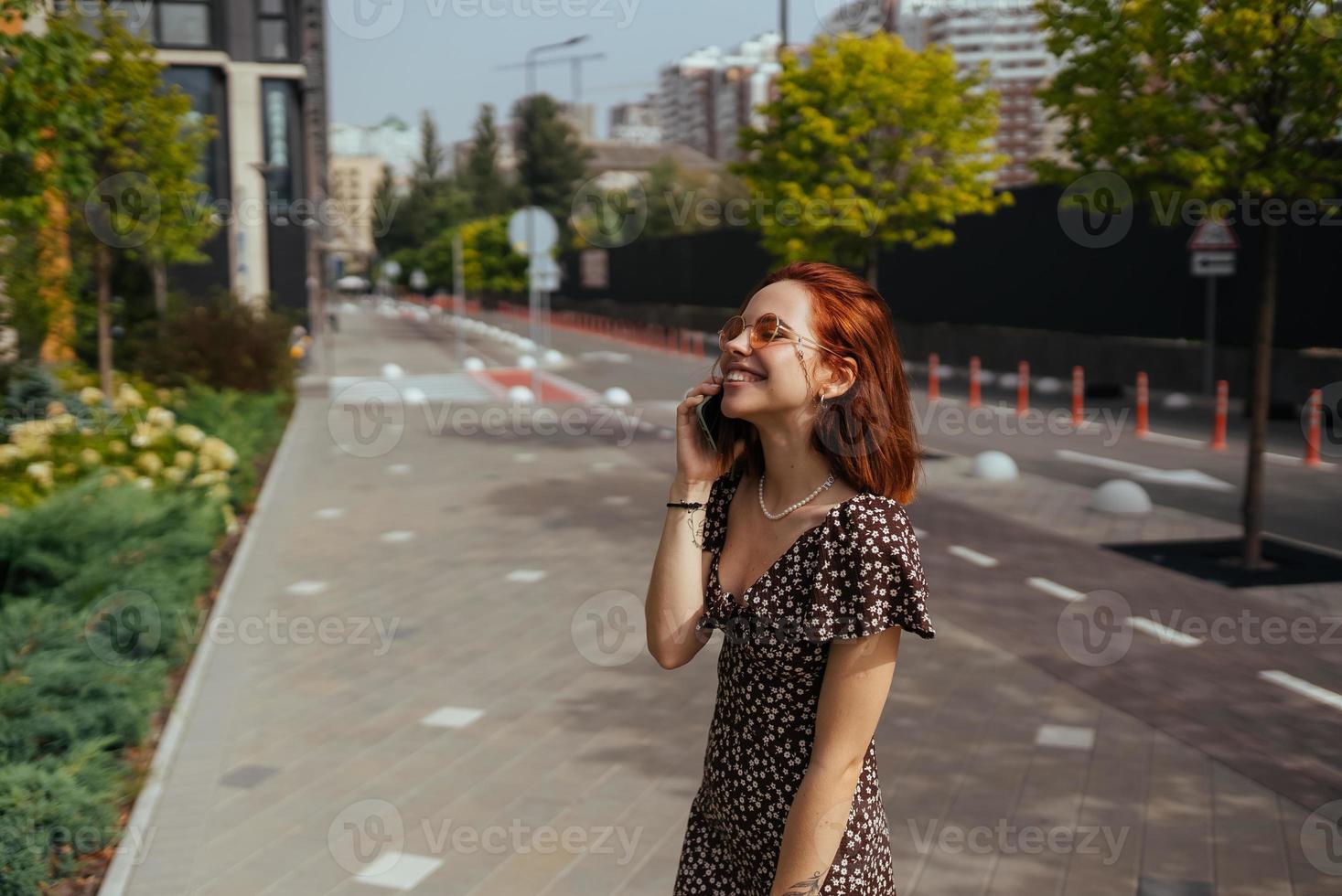 Cute girl talking on mobile phone on modern city background photo