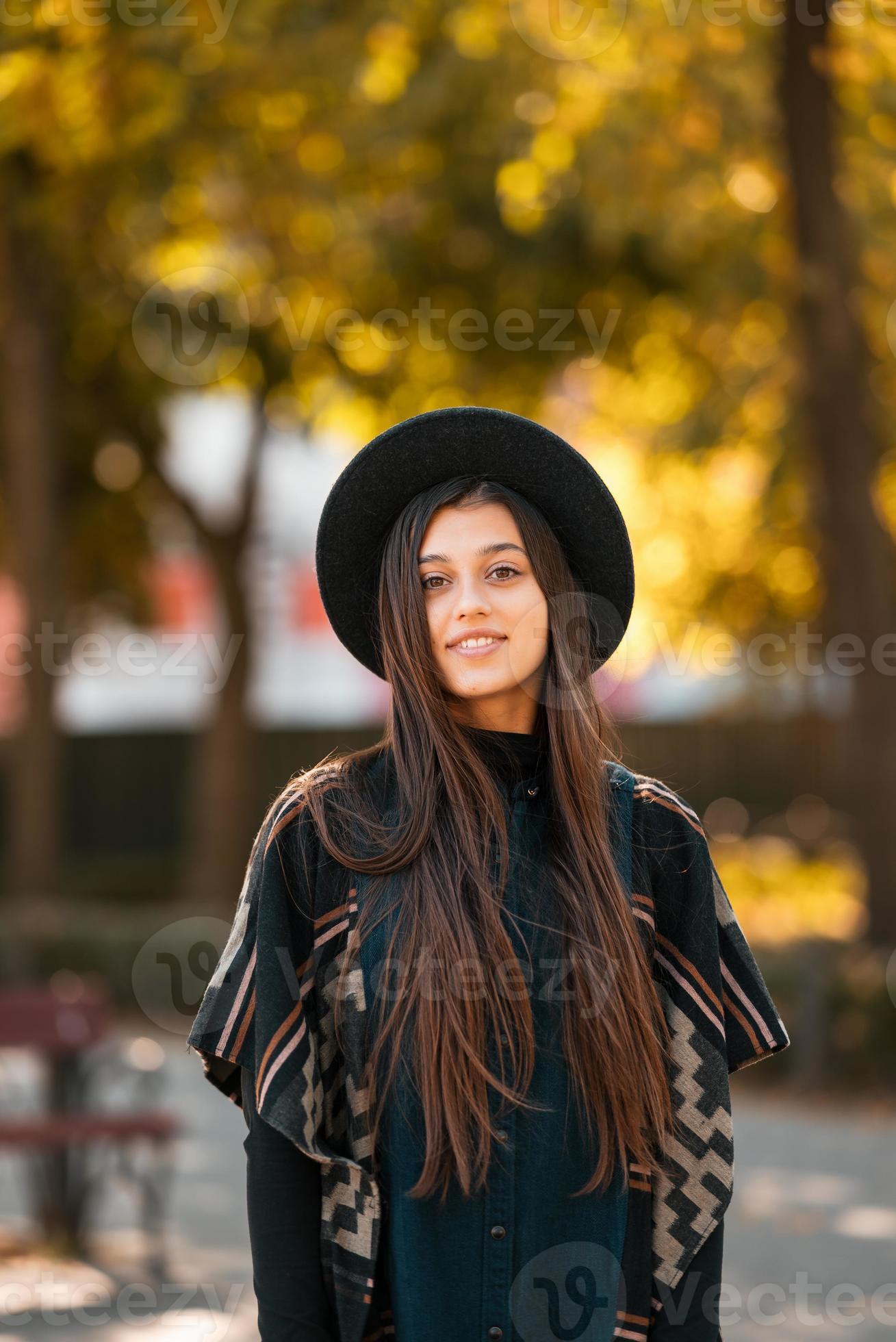 Pelo largo castaño mujer joven bonita en poncho en el parque de